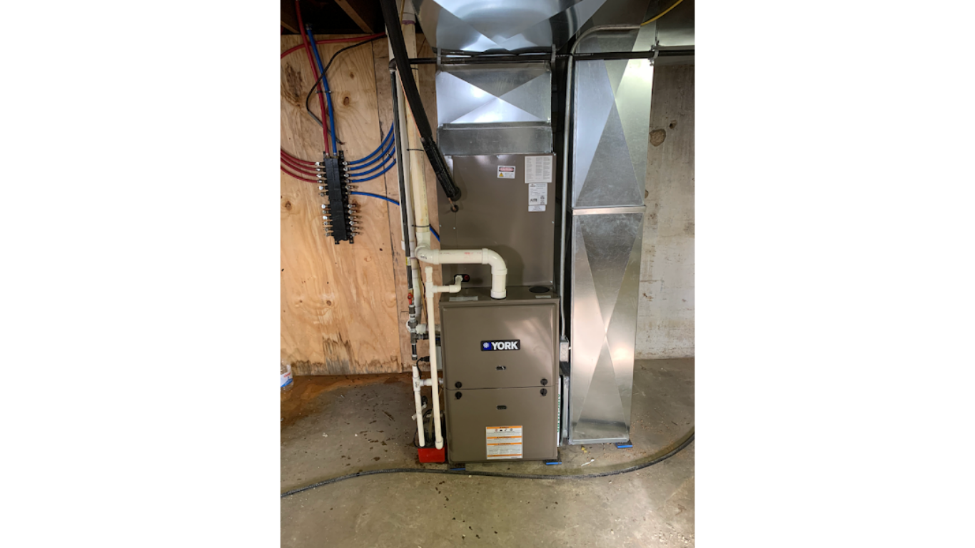 Furnace with connected white pipes in a room under construction.