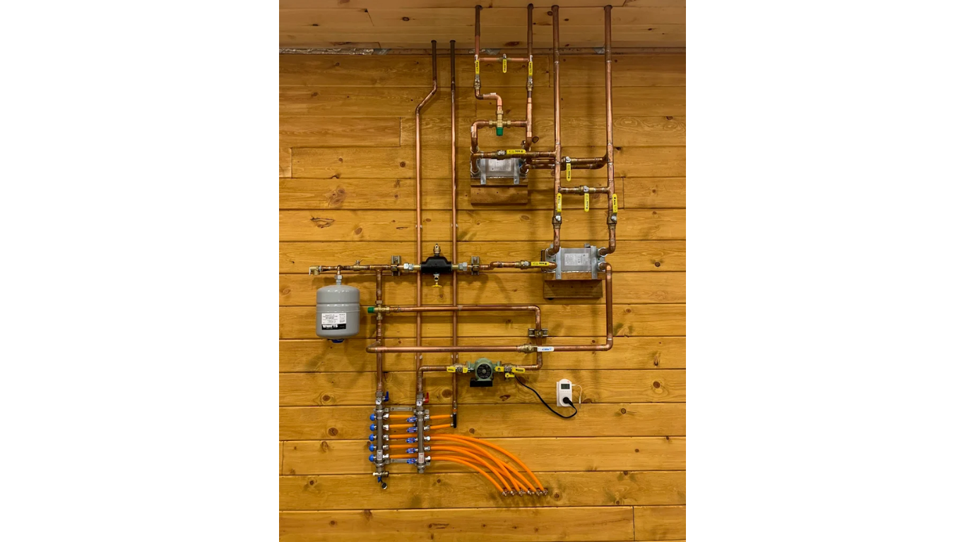 White PVC pipes and electrical boxes on a wooden wall; part of a pool's water system.