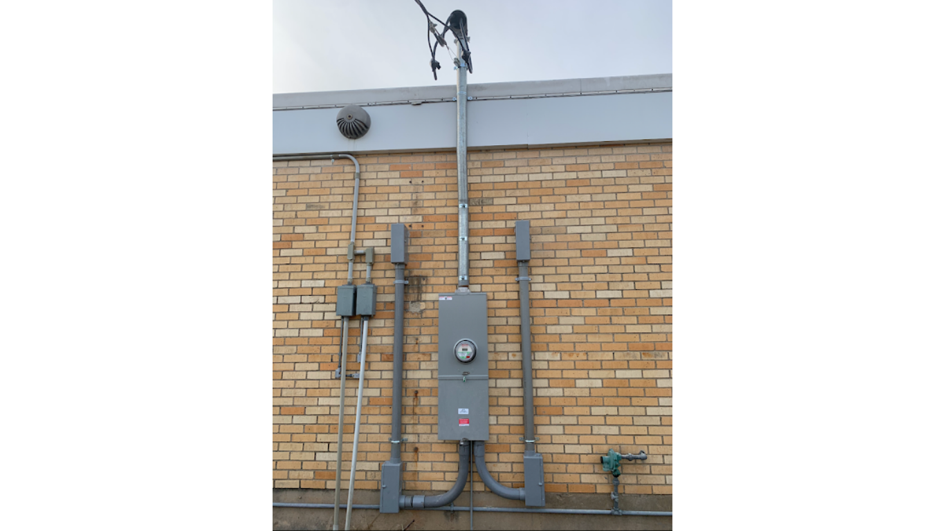 Water filtration system with three blue filters and copper pipes mounted on a brick wall.