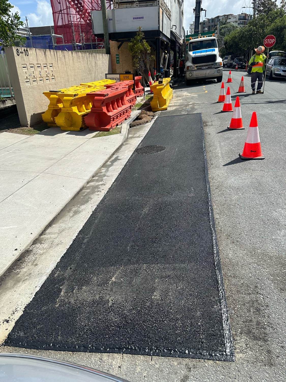 A man is walking down a street next to a row of traffic cones.