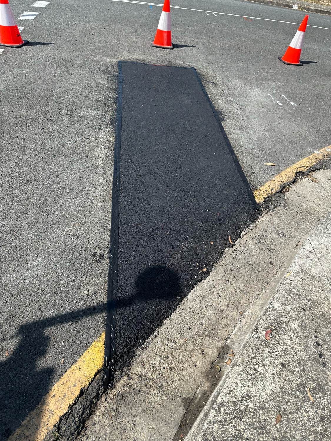 A patch of asphalt on the side of a road next to a curb.