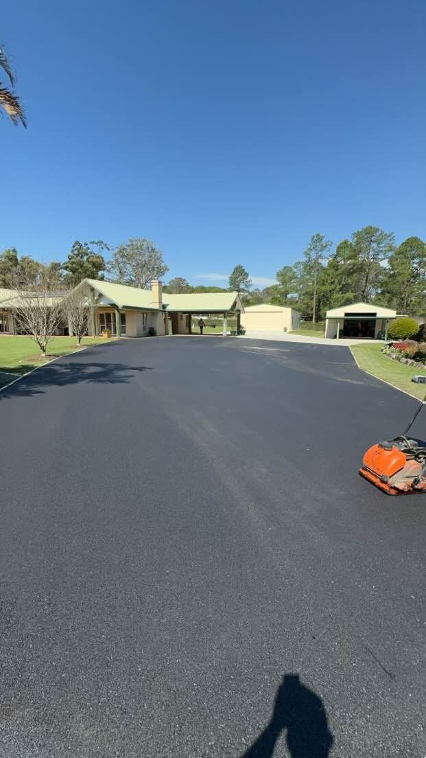 A lawn mower is sitting on the side of a road in front of a house.
