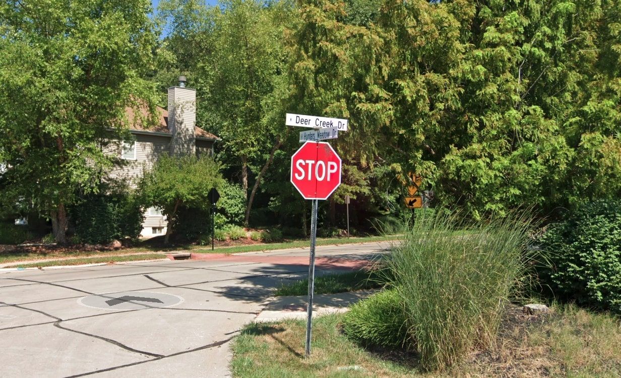 A stop sign surrounded by green trees showcasing the Deer Creek street 