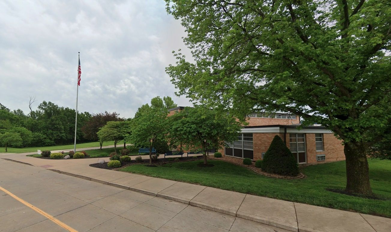 The Forest Park school surrounded by trees and an American Flag