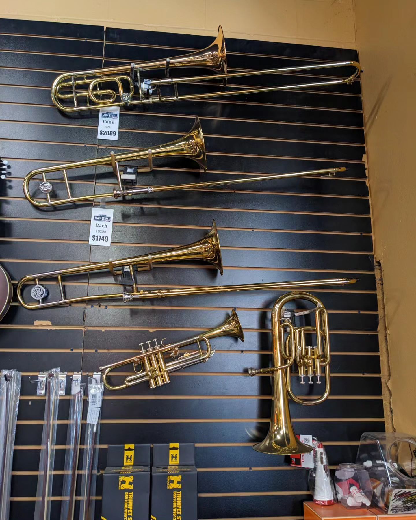 several brass Instruments hanging on a wall in a store