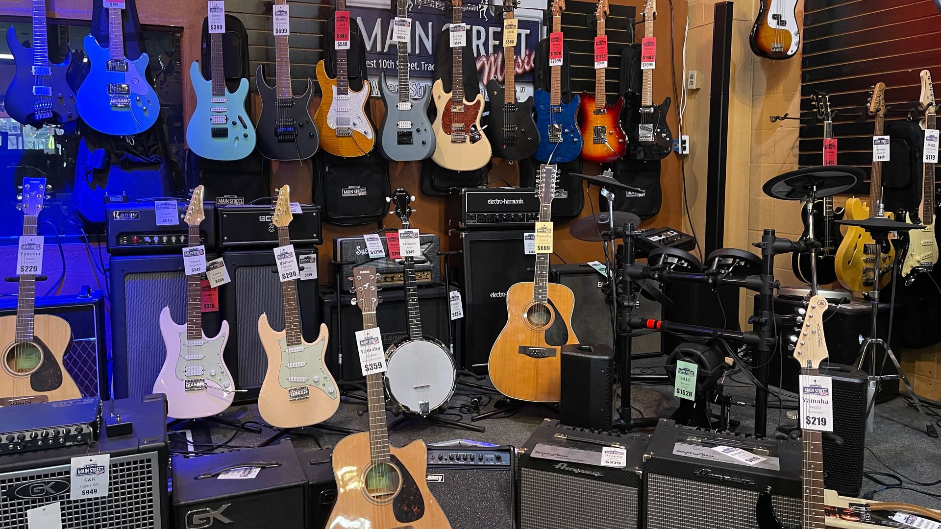 A bunch of guitars are hanging on a wall in a store.