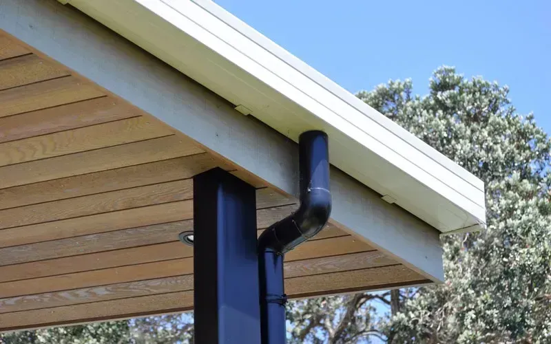 Modern white box gutter system with a black downpipe on a house