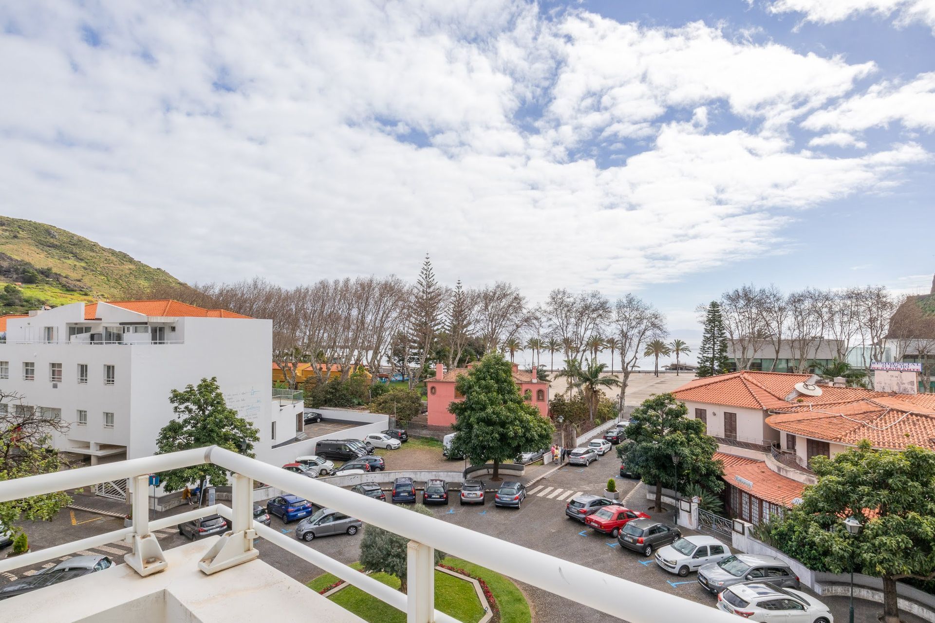 a balcony overlooking a parking lot with cars parked in front of a building .