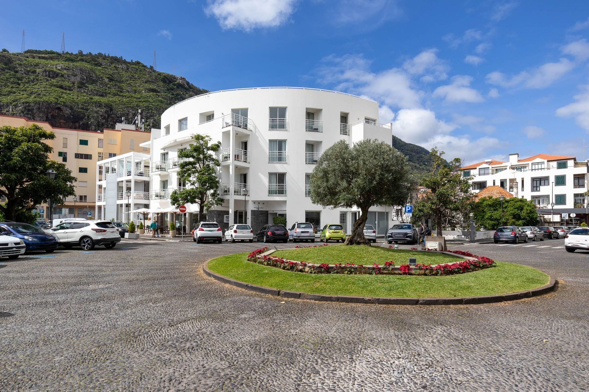 a large white building with a lot of cars parked in front of it .