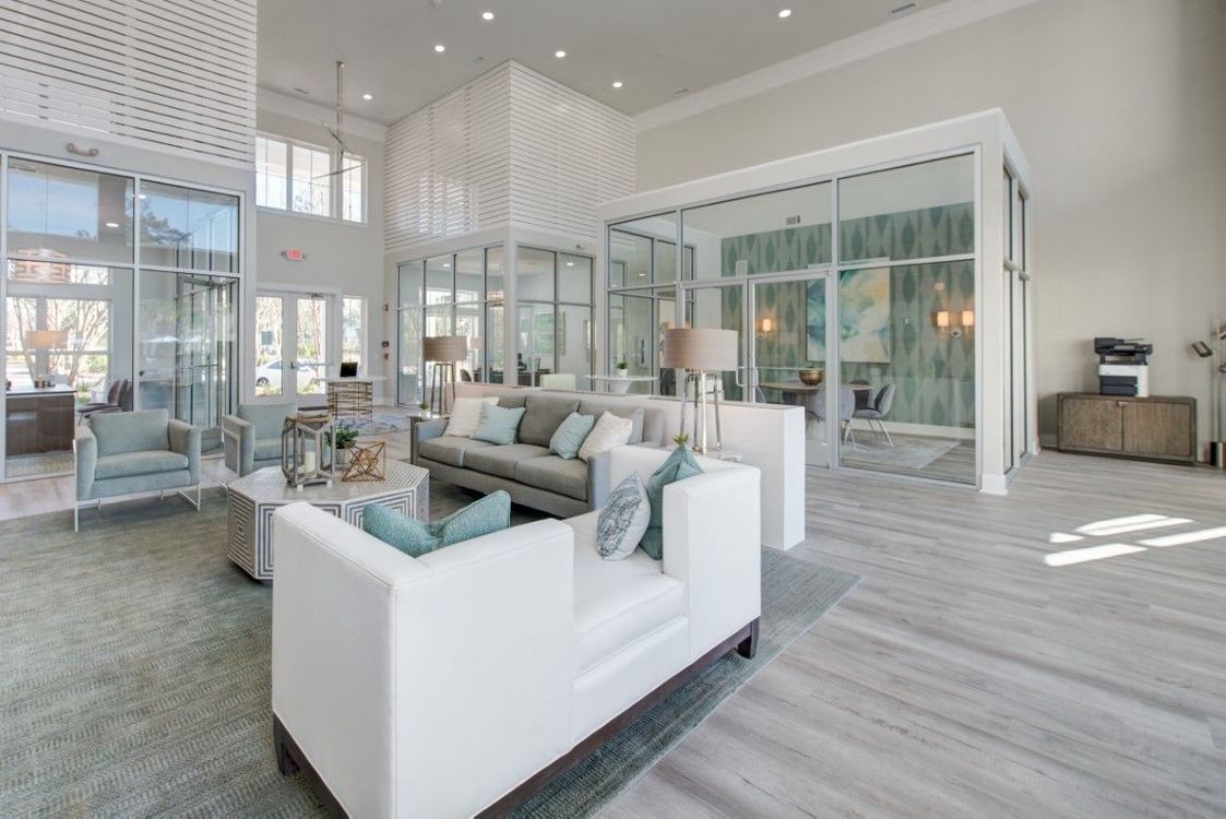 High ceiling apartment clubhouse with sofa and oversized windows.