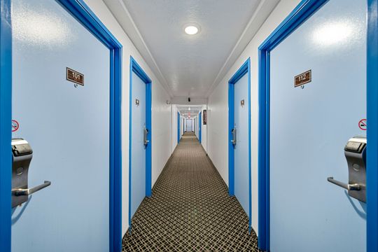 Hotel hallway with light blue doors and patterned carpet.