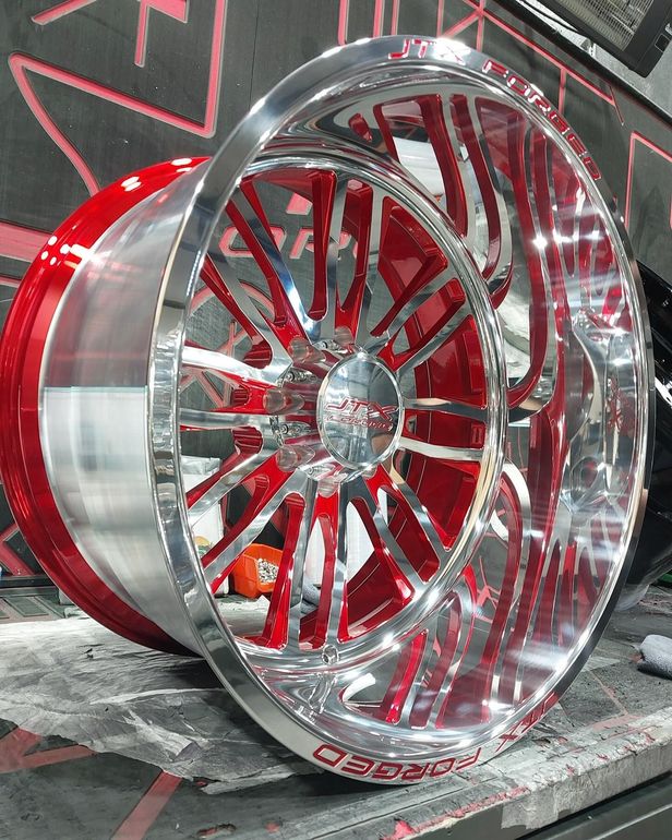 A pair of red and chrome wheels are sitting on a table.