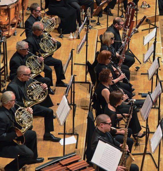 French horns, clarinets and bassoons playing in concert