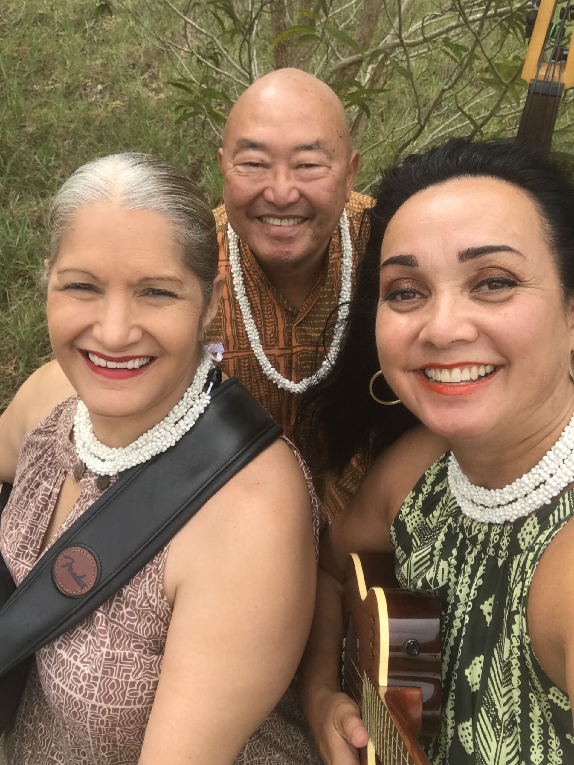 A man and two women are posing for a picture while one woman is holding a guitar.