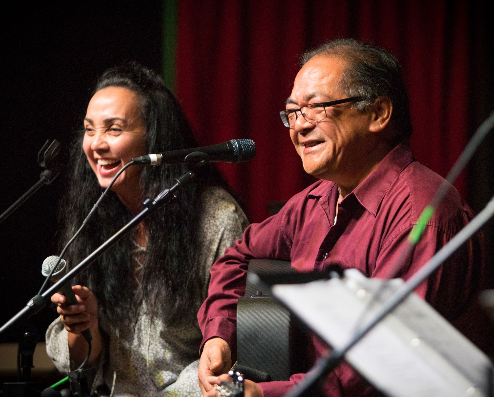 A man and a woman are singing into microphones on a stage.