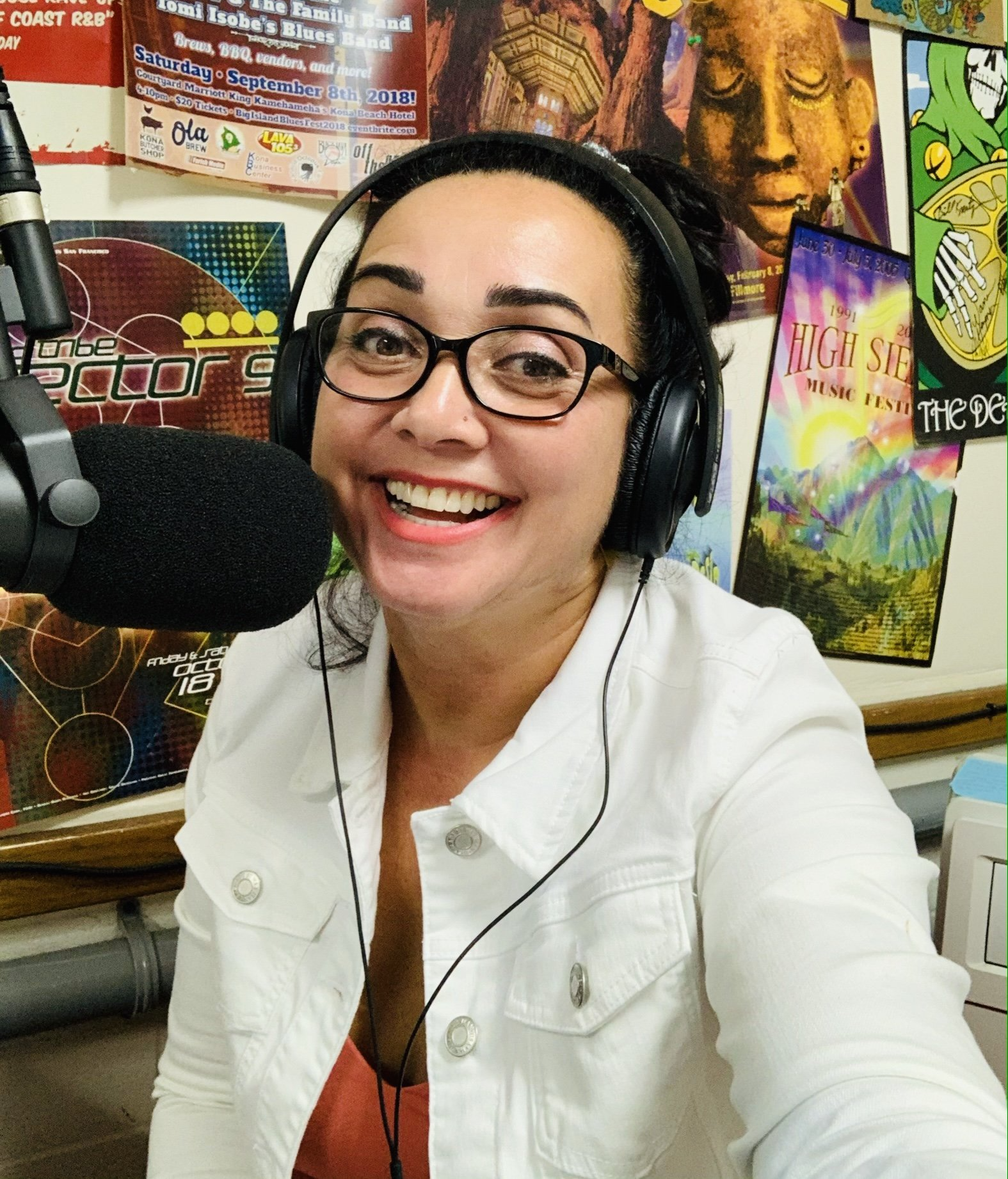 A woman wearing headphones is smiling in front of a microphone