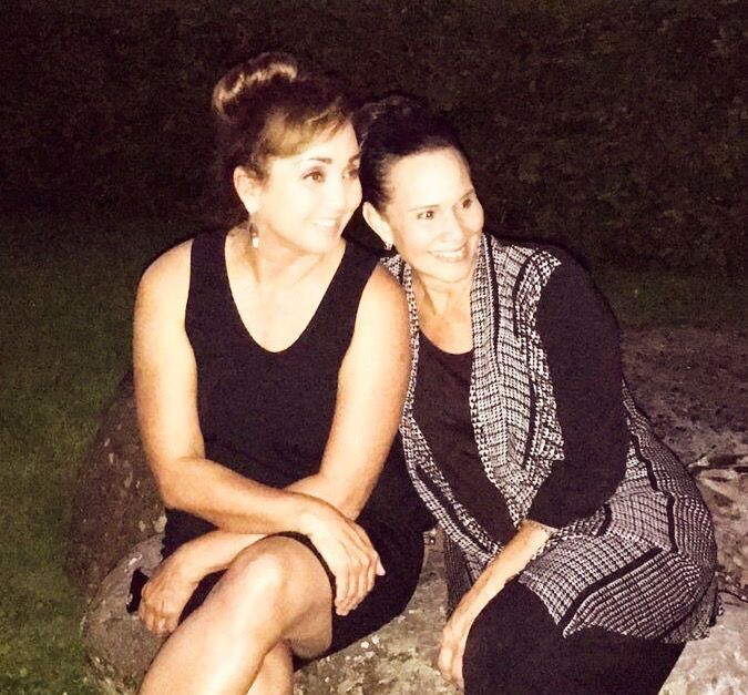 Two women are sitting next to each other on a rock