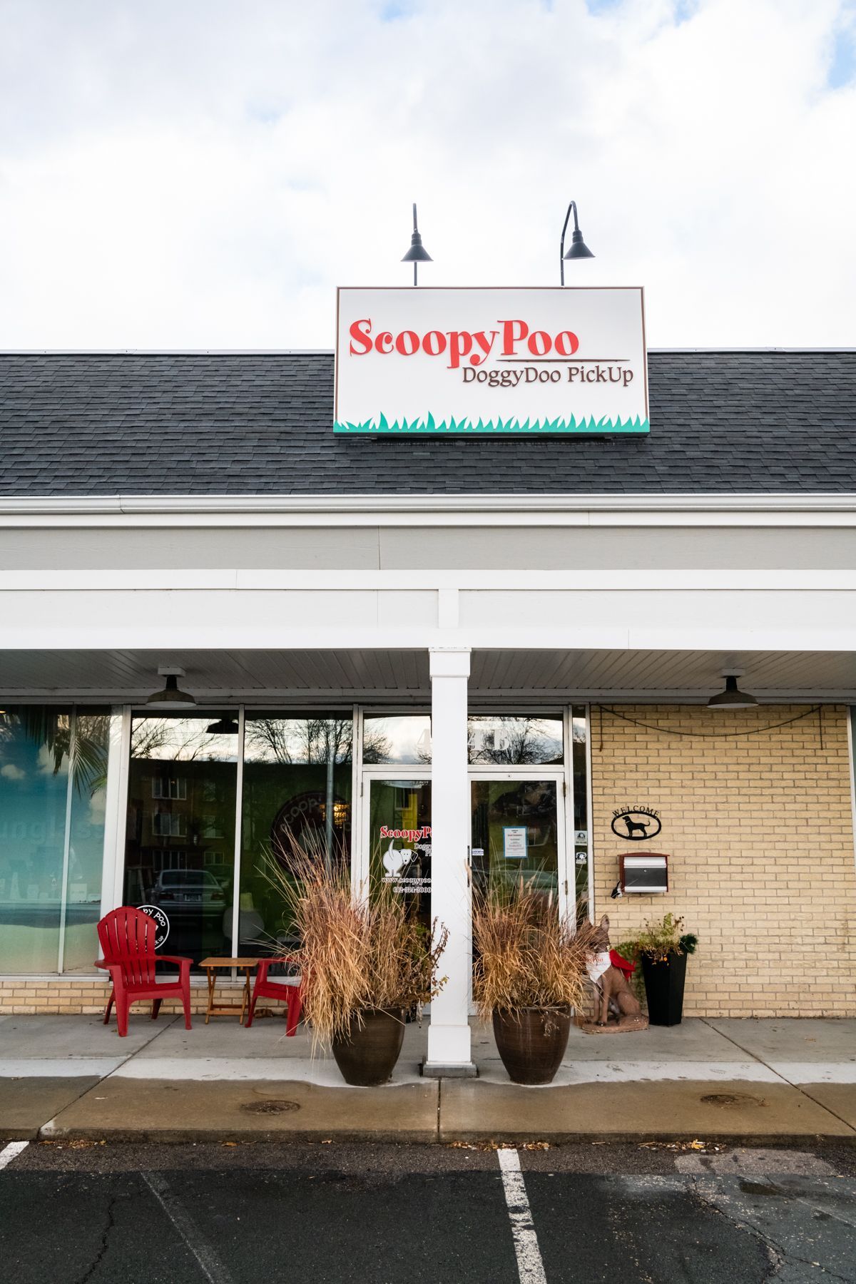 Scoopy Poo doggy-doo pick-up storefront with sign, glass doors, and potted plants.