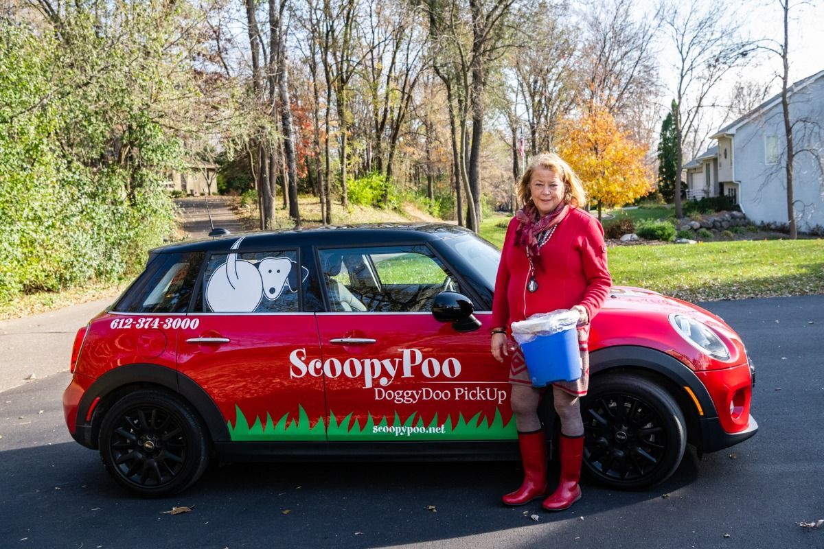 Woman in red outfit stands next to a red Mini Cooper with 