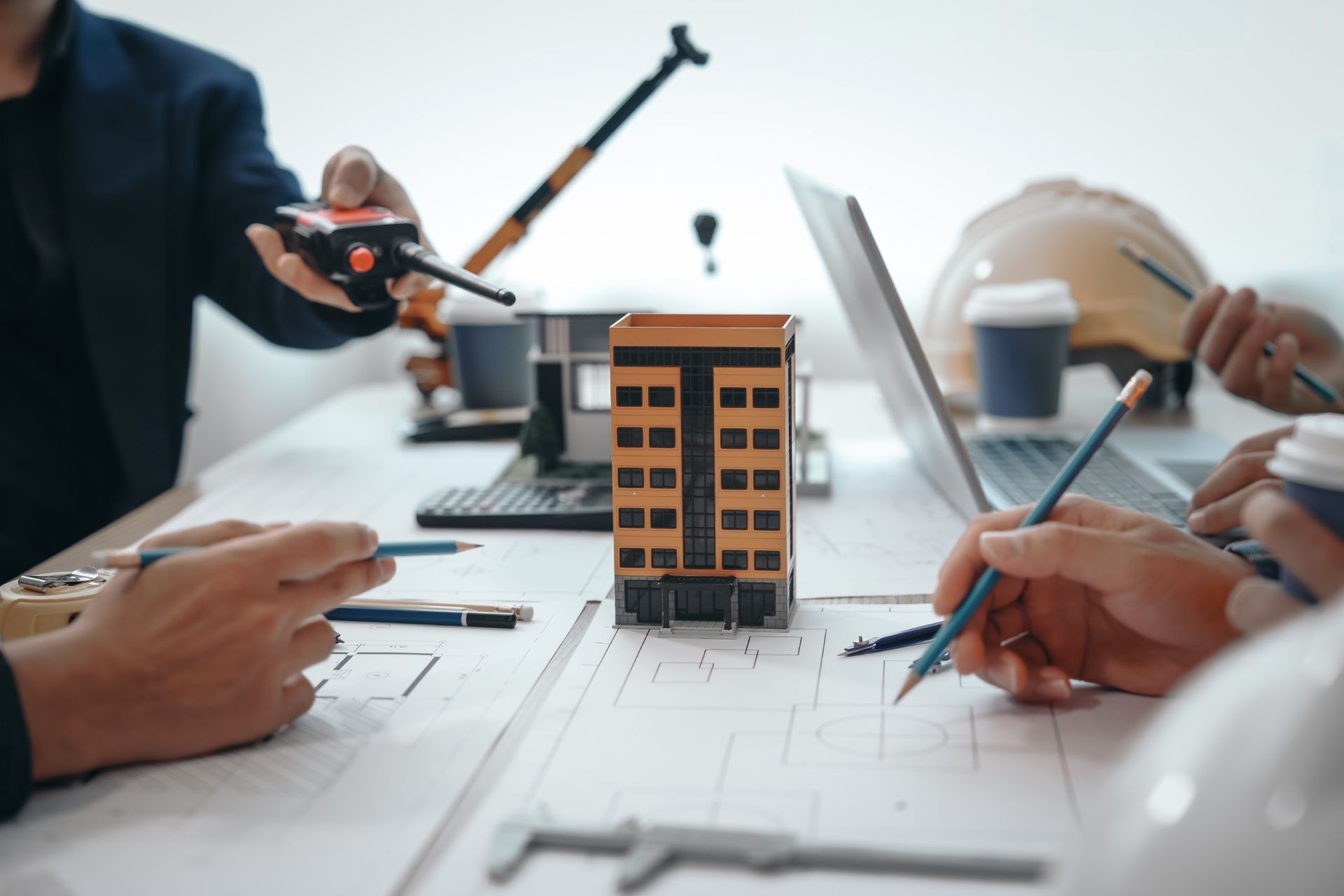 A group of people are sitting at a table with a model of a building.