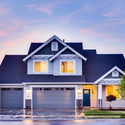 A large house with a blue roof and two garage doors.