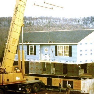 A yellow crane is lifting a blue house