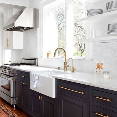A kitchen with black cabinets , a sink , a stove , and a window.