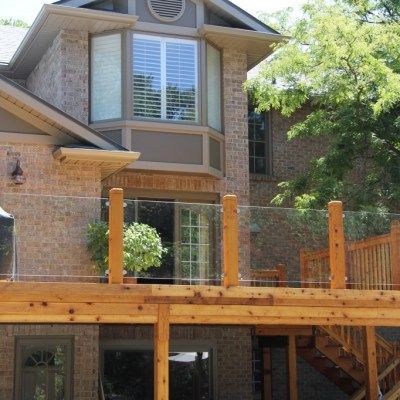 A brick house with a wooden deck and glass railing