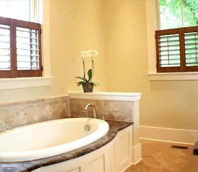 A bathroom with a tub and a window with shutters