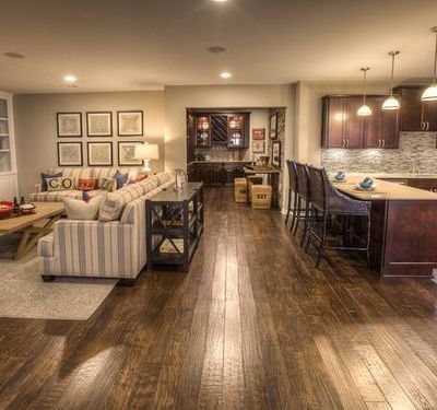 A living room filled with furniture and a kitchen with hardwood floors.