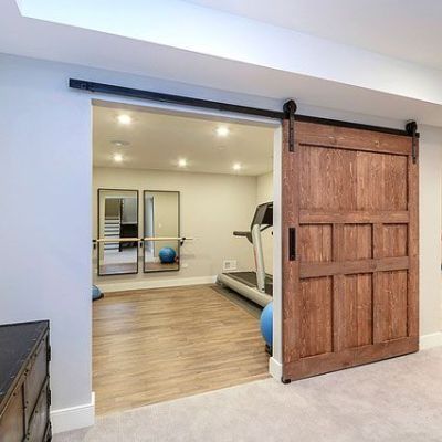 A sliding barn door opens to a gym in a basement.