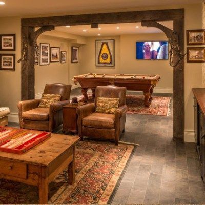 A living room with a pool table , chairs , a coffee table and a television.