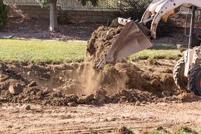 A bulldozer is scooping dirt into a hole in the ground.