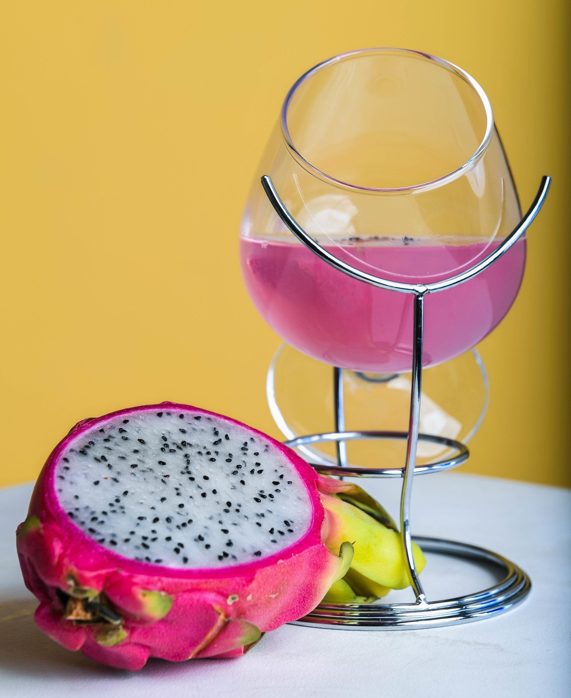 A dragon fruit next to a glass of pink liquid