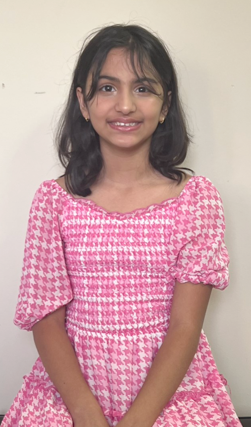 A young girl is playing a violin in a room.