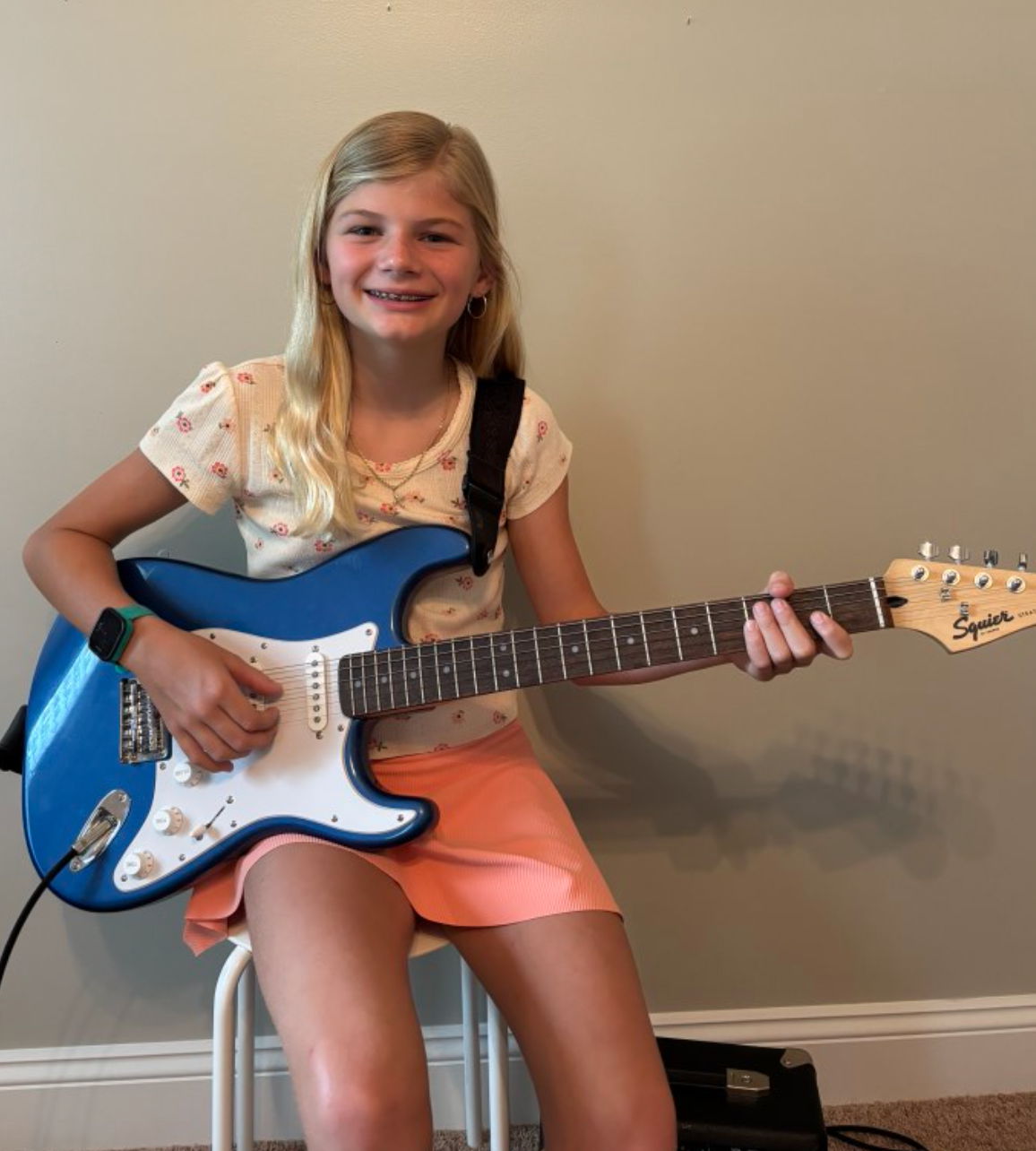 A young girl is playing a violin in a room.