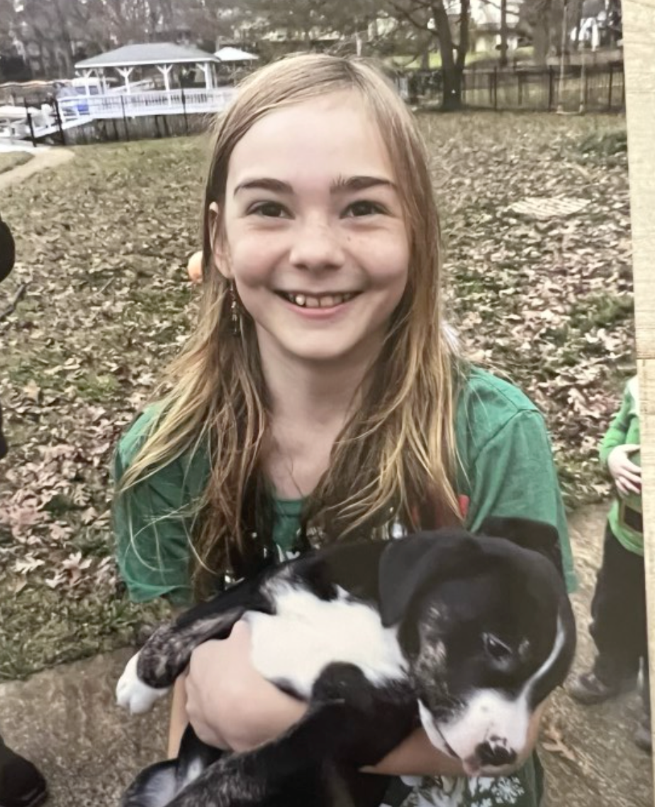 A younggirl wearing glasses and a light blue cardigan