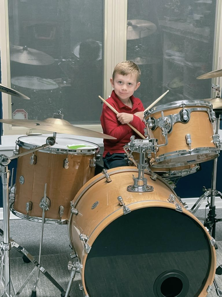 A young boy is playing drums in a sound room.