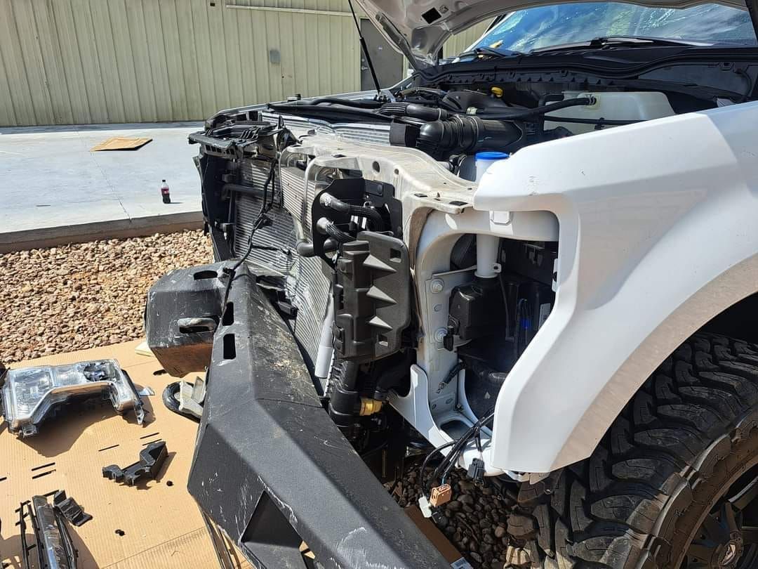 A white truck with the hood open is being repaired.