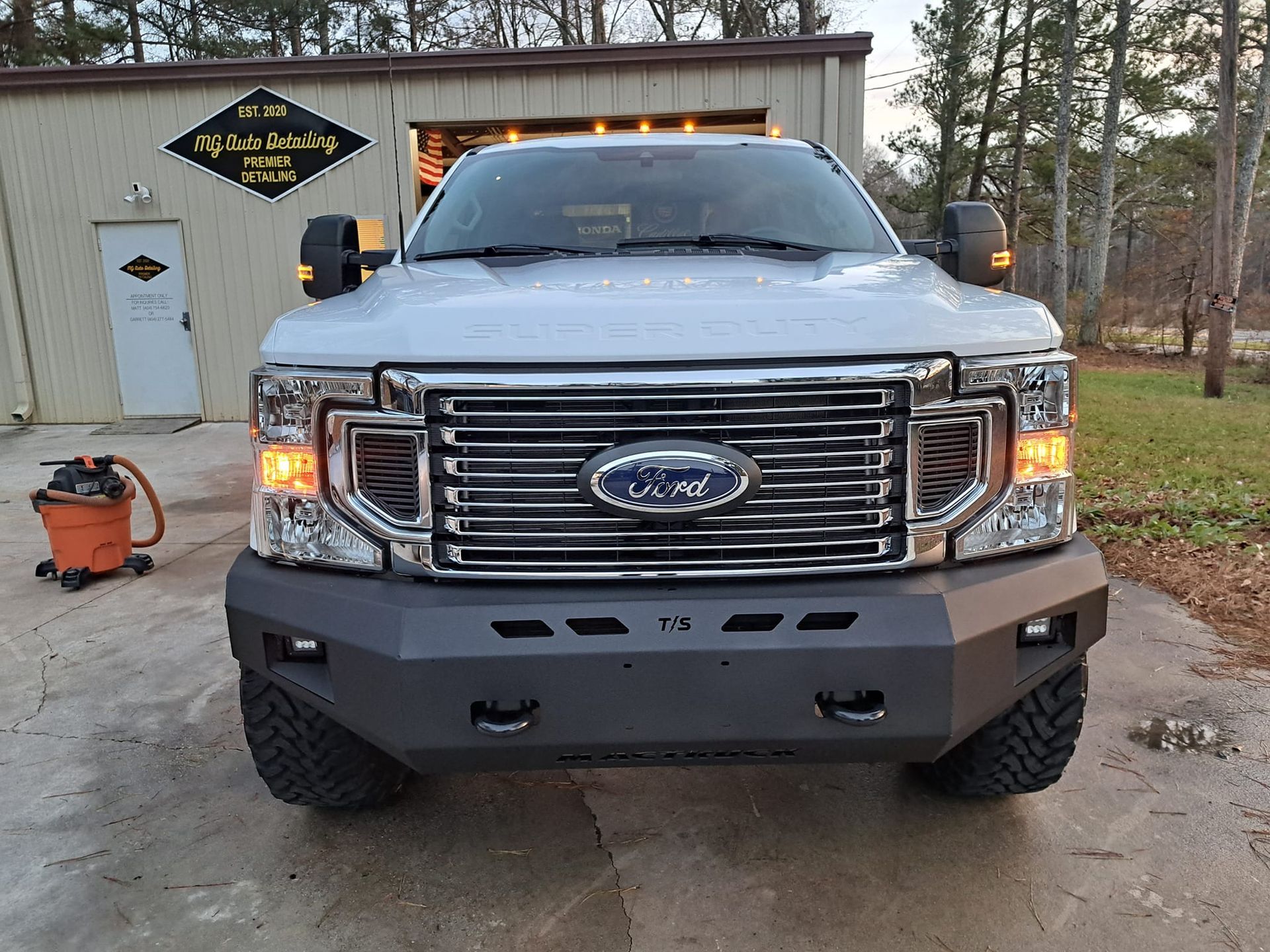 A silver ford truck is parked in front of a garage.