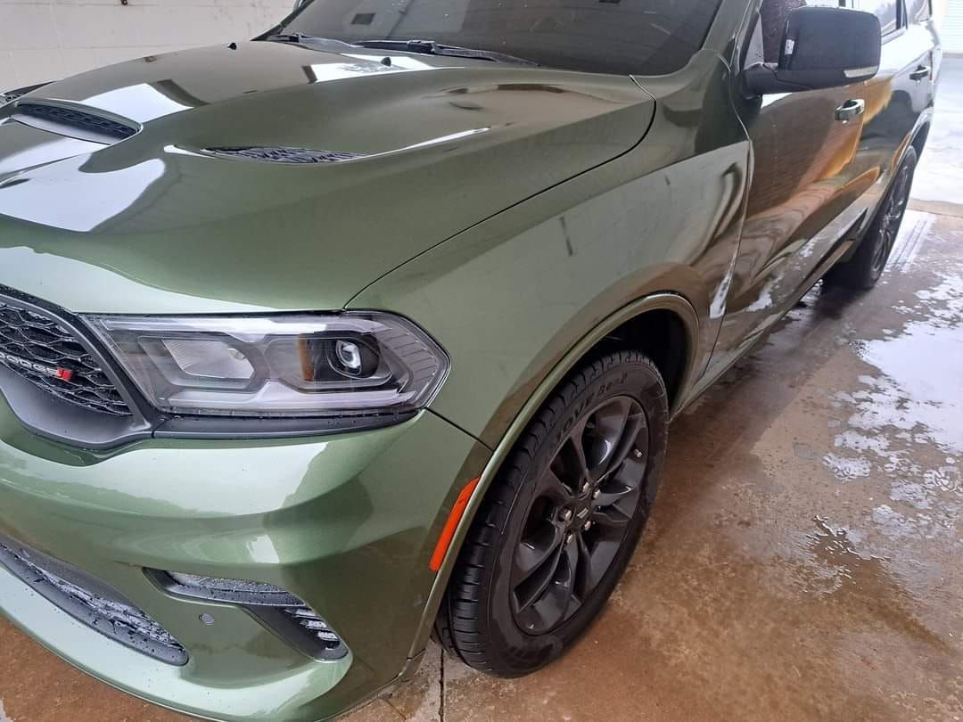 A green dodge durango is parked in a garage.