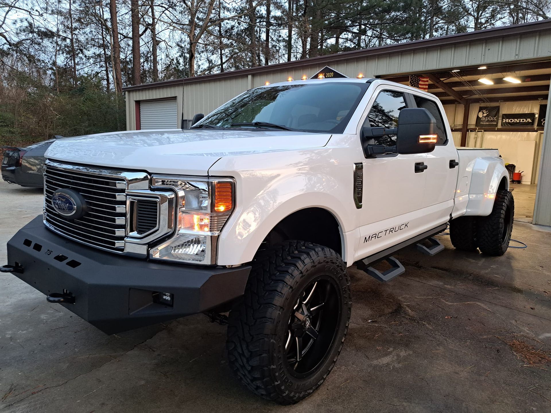 A white ford truck is parked in front of a garage.