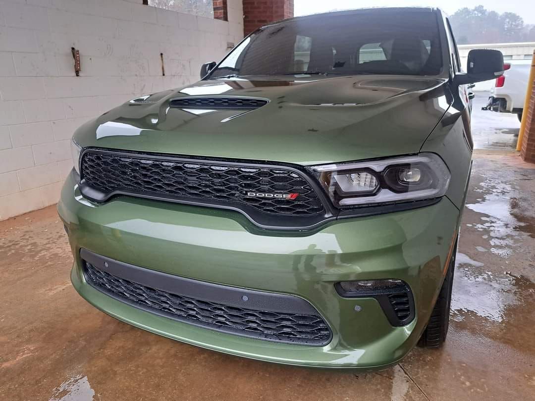 A green dodge durango is parked in a garage.