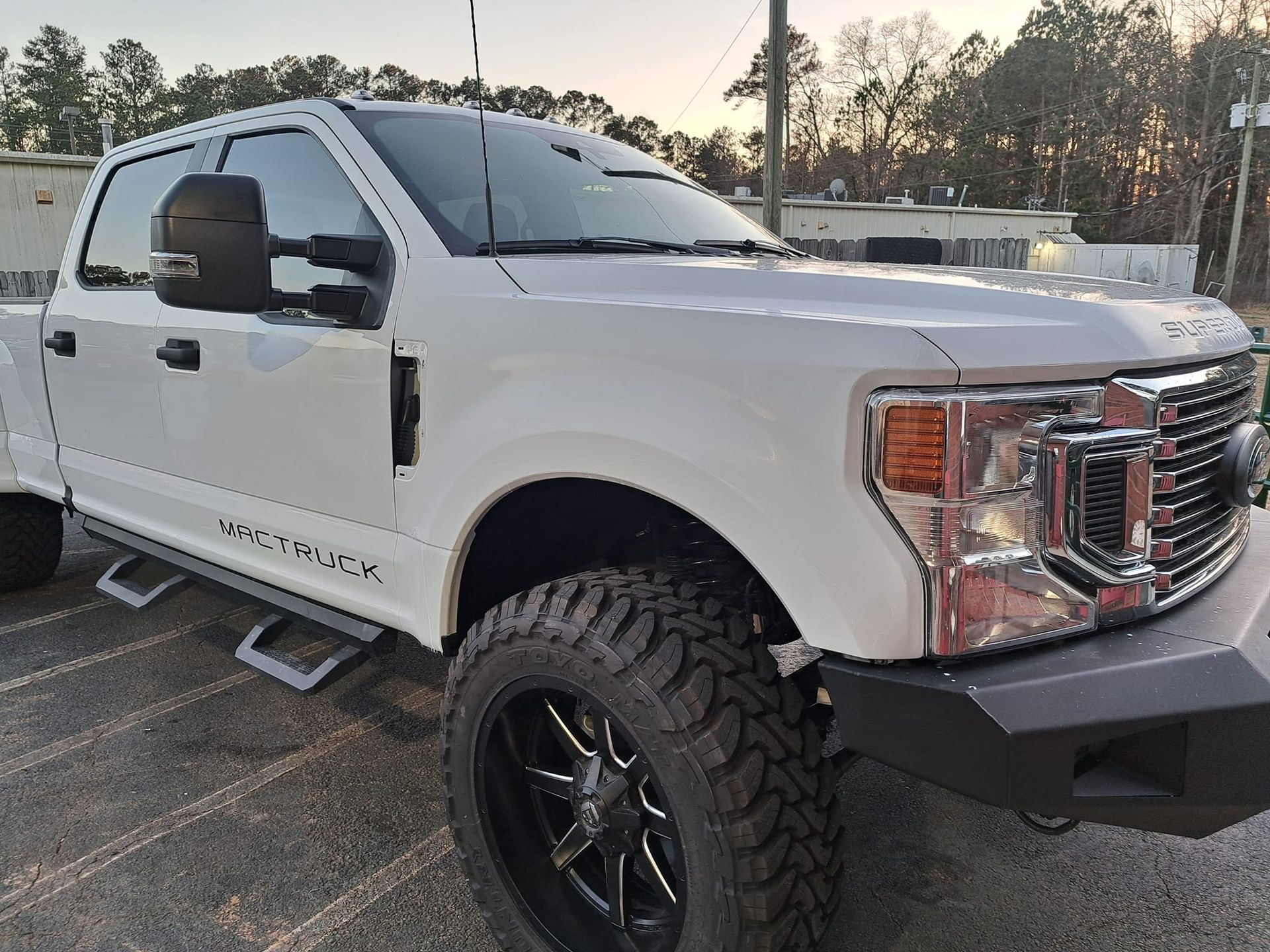 A white truck with black wheels is parked in a parking lot.