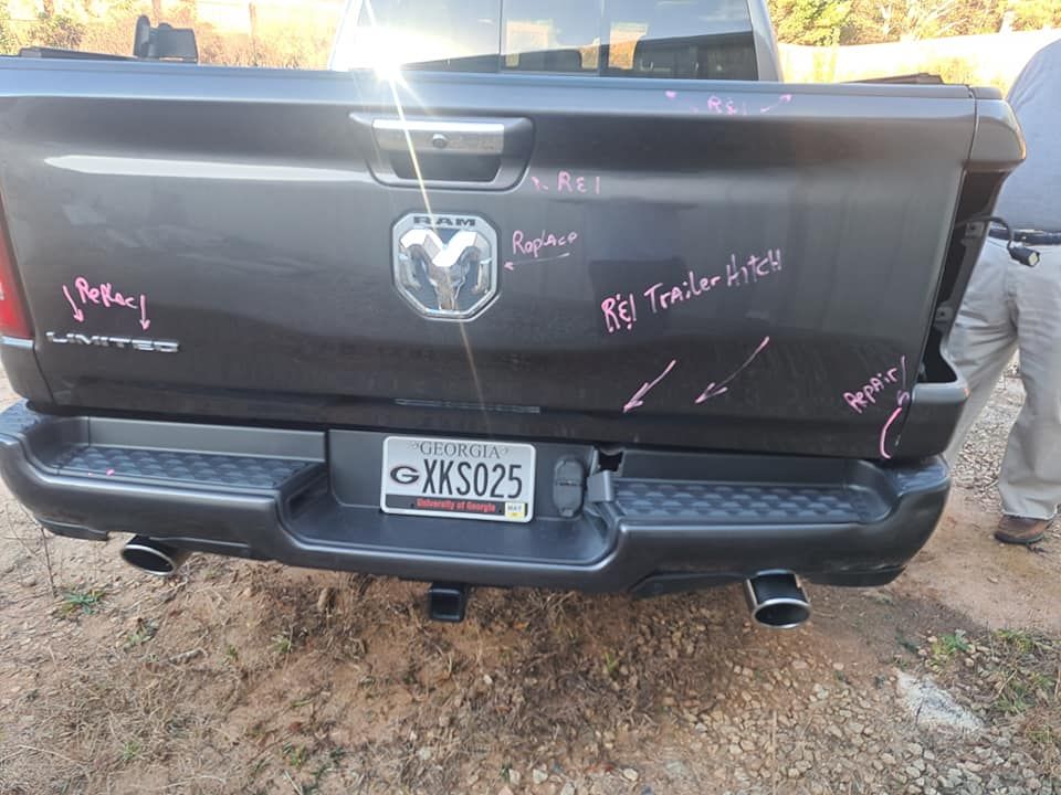 A man is standing next to a ram truck with a license plate that says xks025