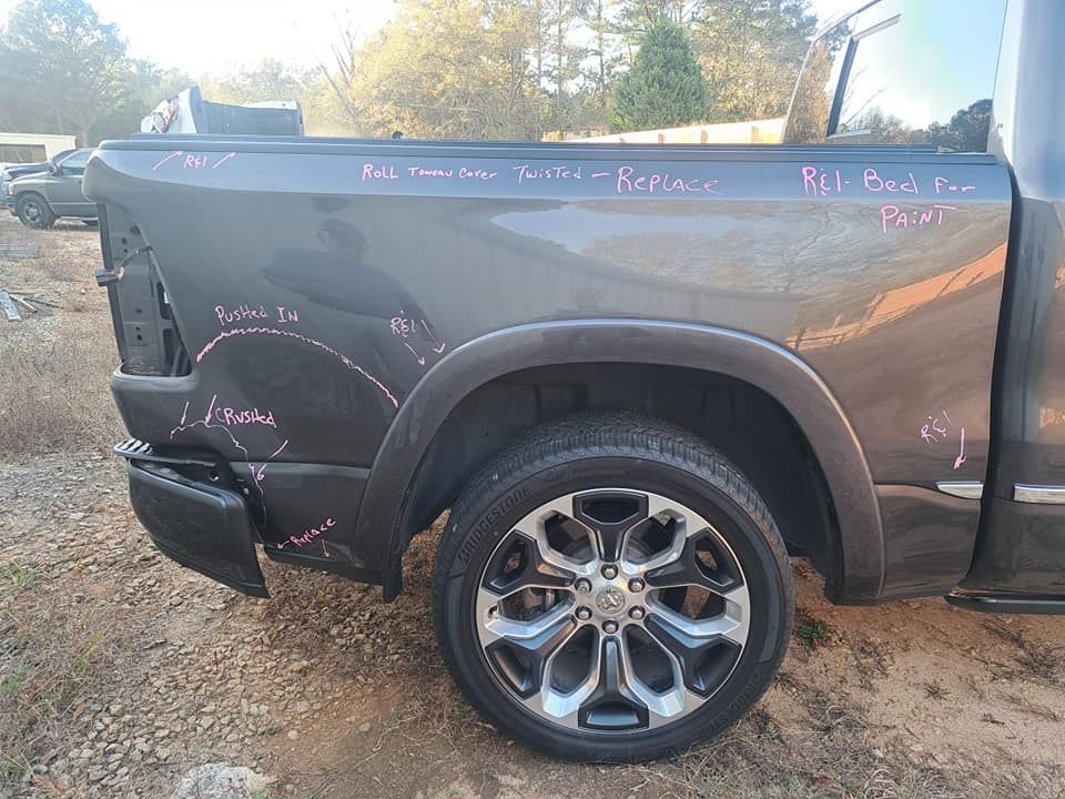 A ram truck is parked in a gravel lot.