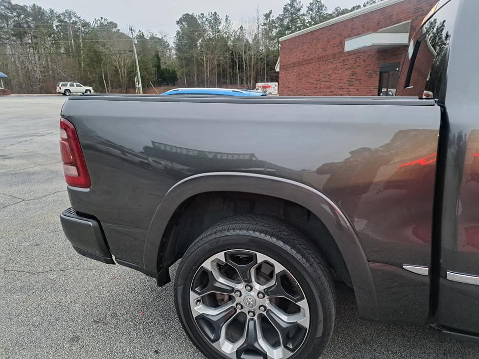 A gray ram truck is parked in a parking lot in front of a brick building.