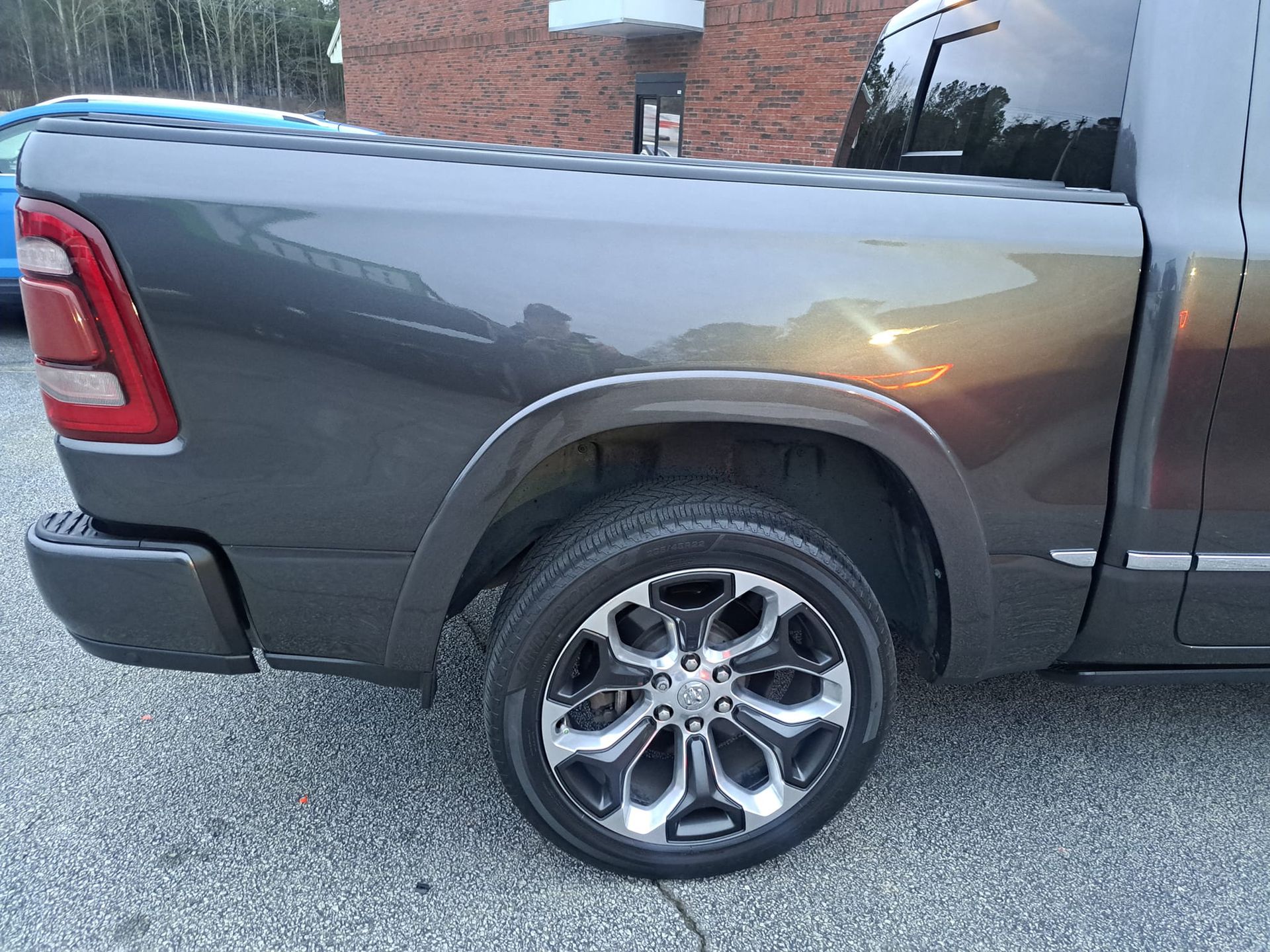 A gray dodge ram truck is parked in front of a brick building.