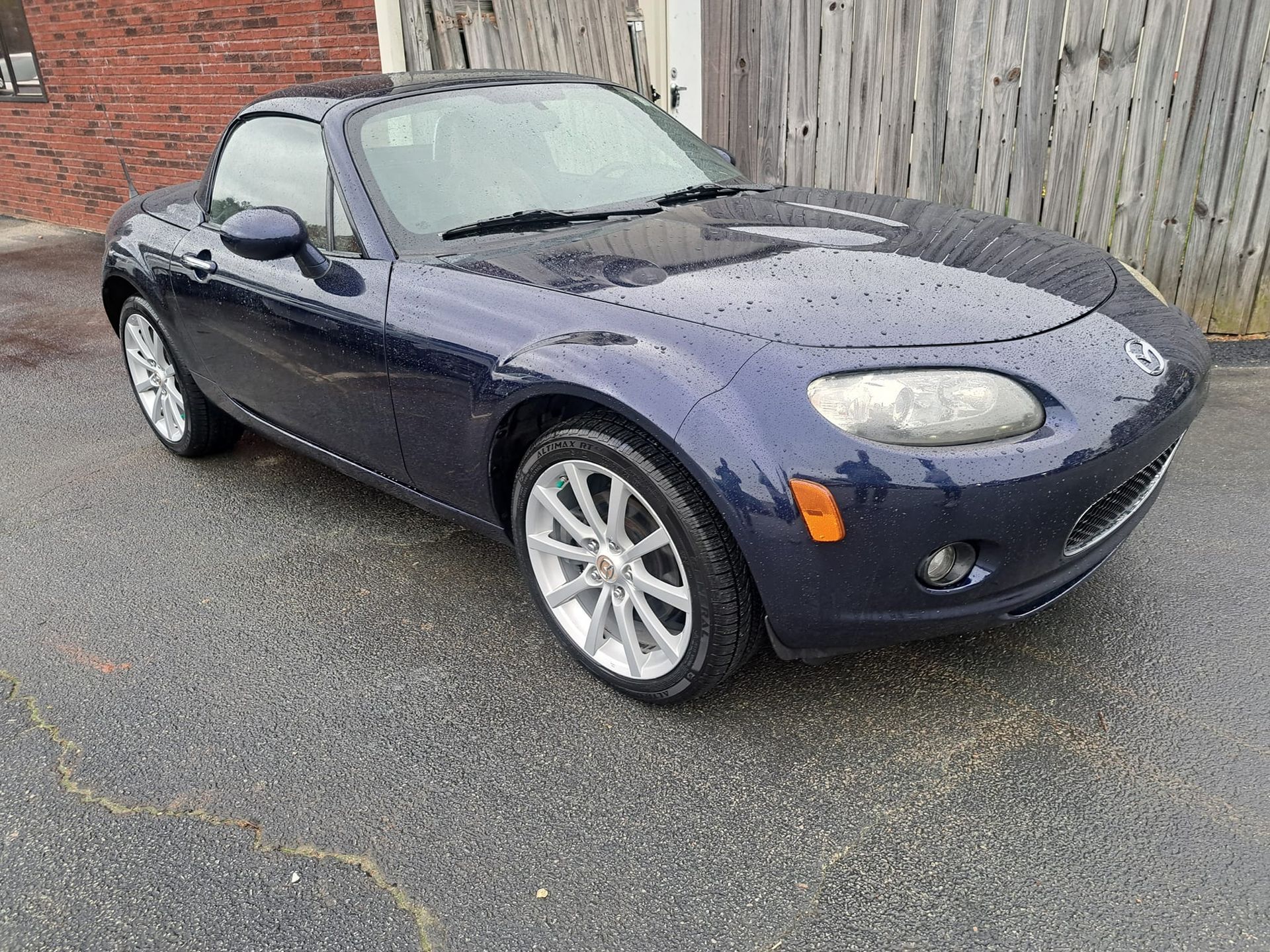 A blue sports car is parked in front of a brick building.