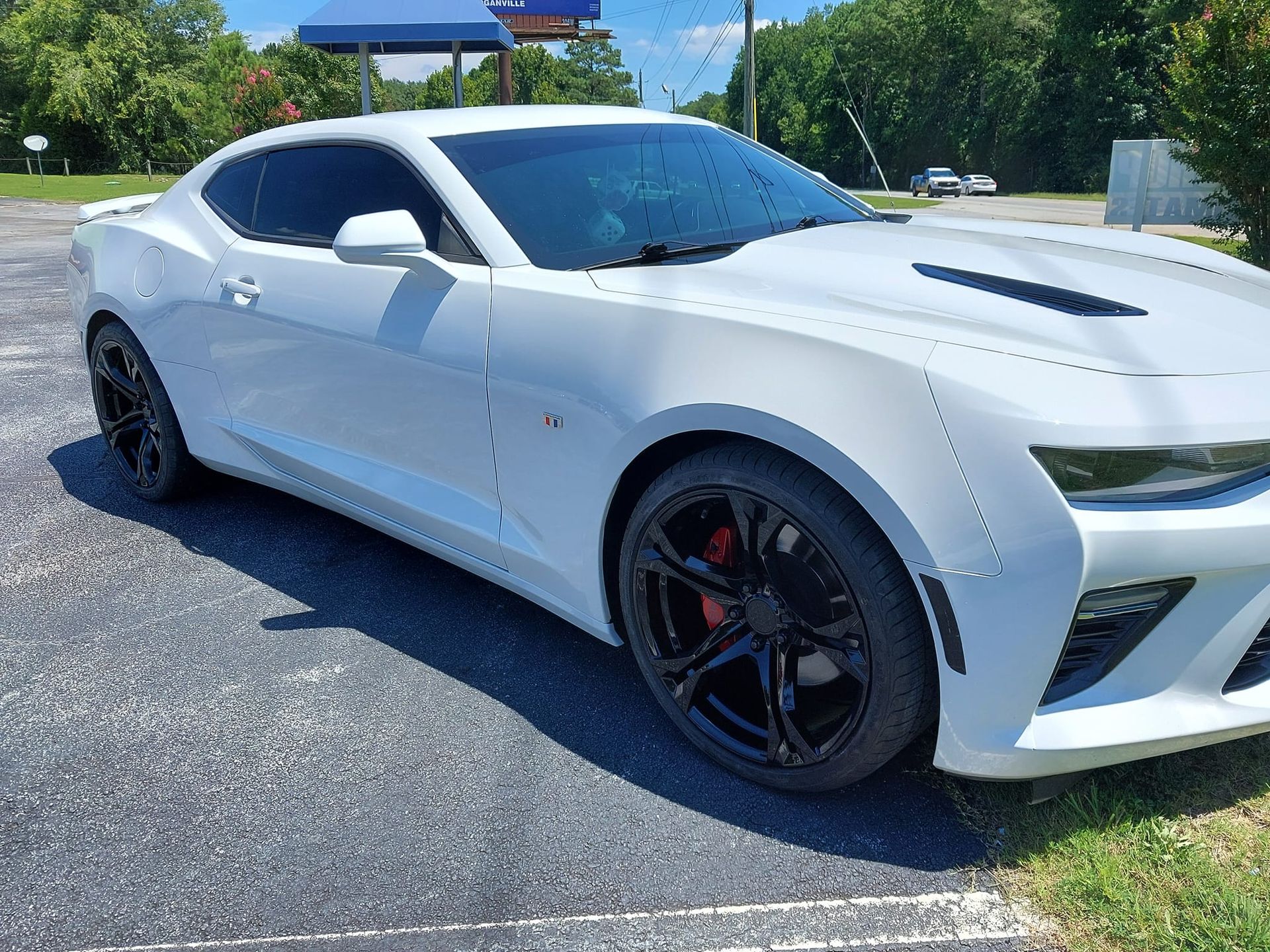 A white chevrolet camaro is parked in a parking lot.